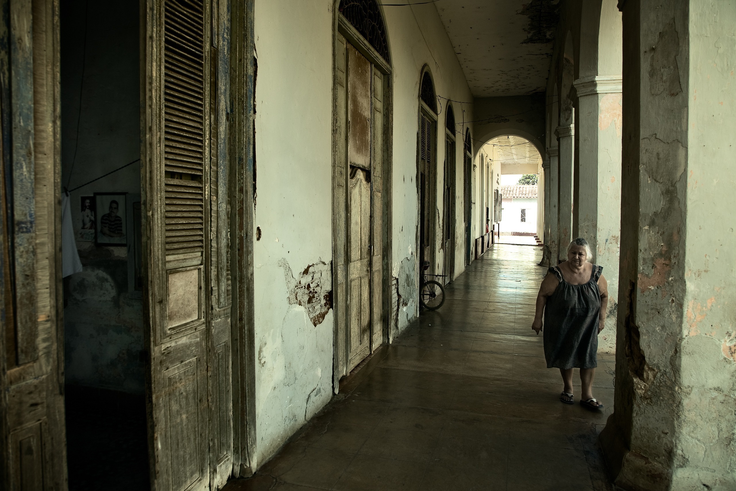 Femme dans un couloir à arcades aux façades défraîchies, Caibarién, Villa Clara, Cuba