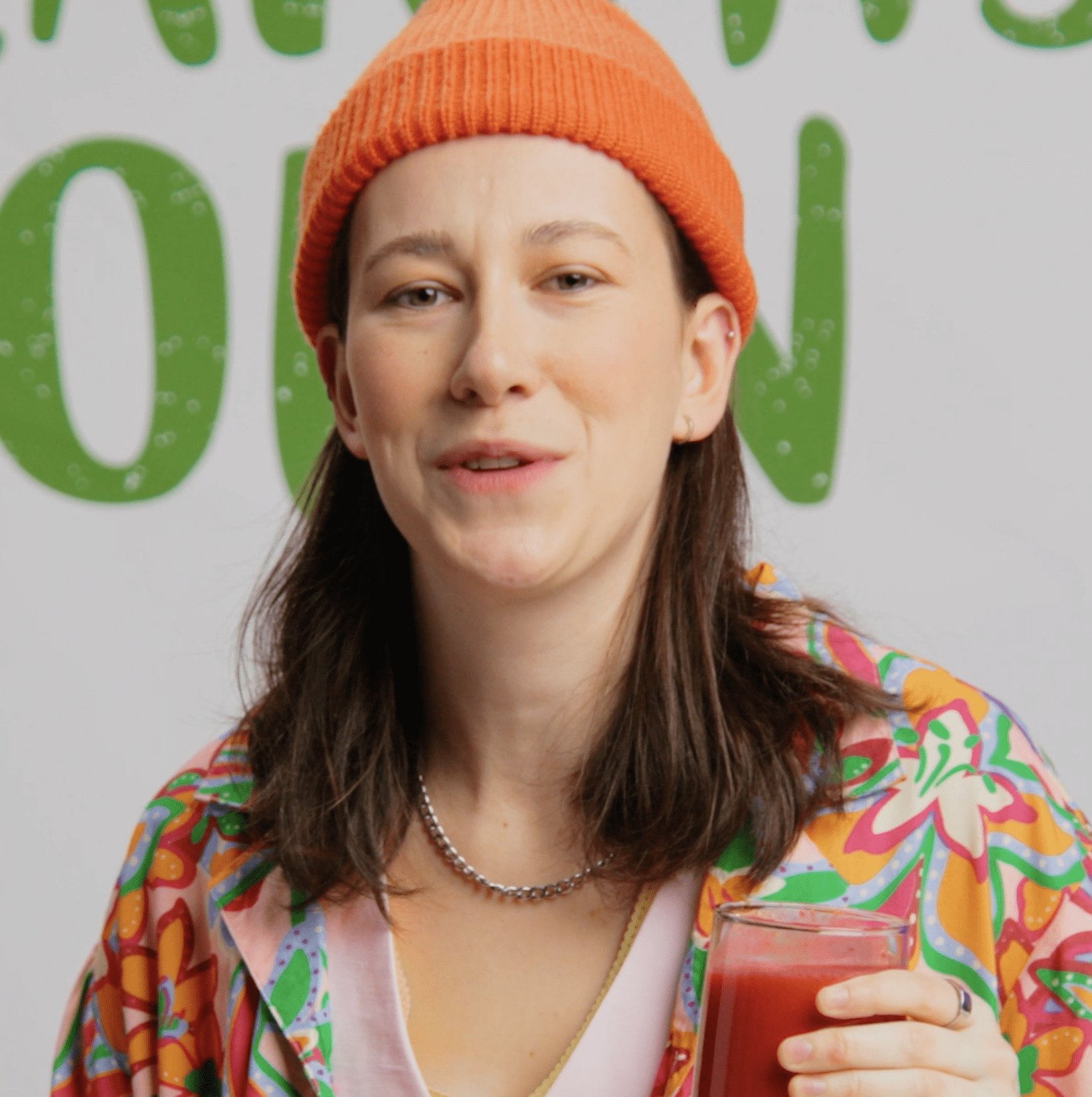 Femme à la tuque orange tenant un verre de boisson végétale, campagne Imprononçable de Earth’s Own