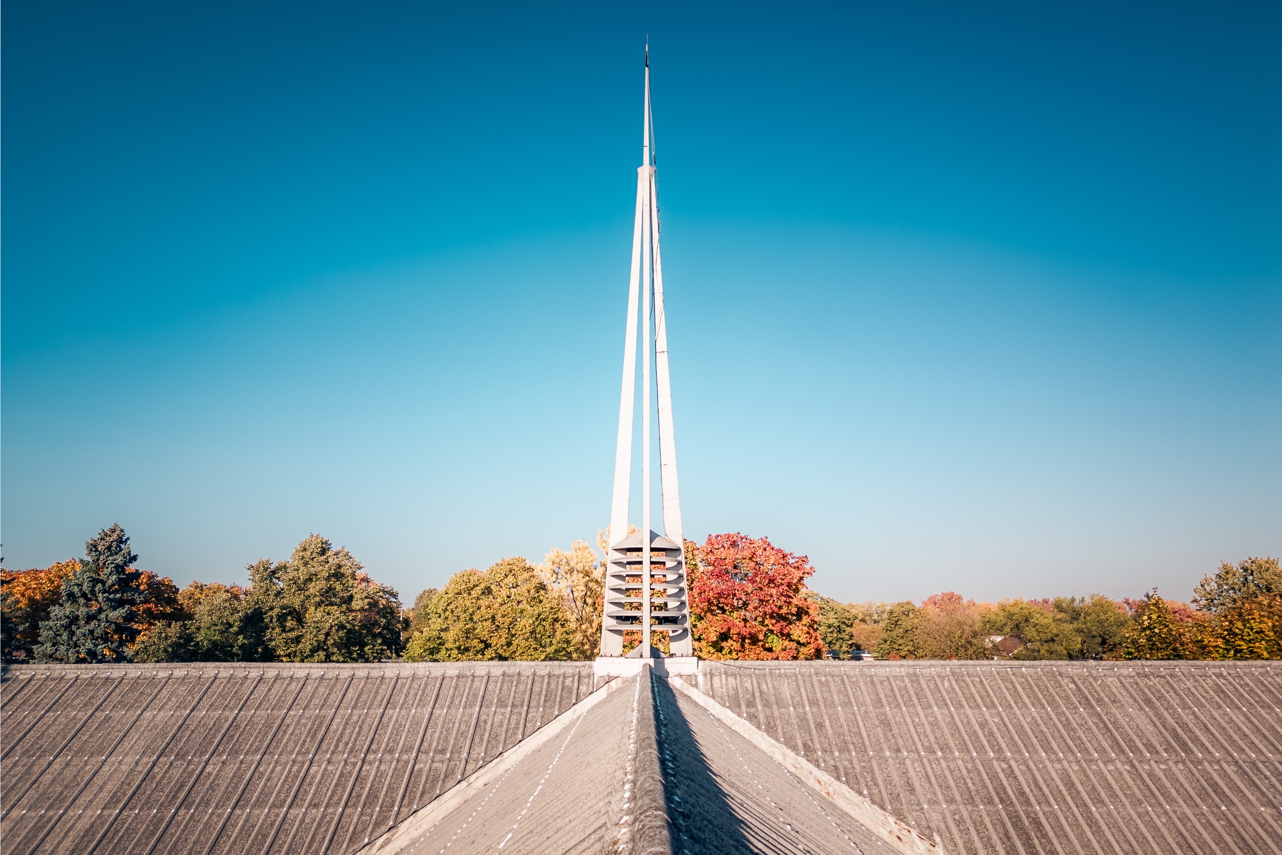 Flèche et faîte du toit d’une église moderniste sur ciel bleu, Ahuntsic, Montréal