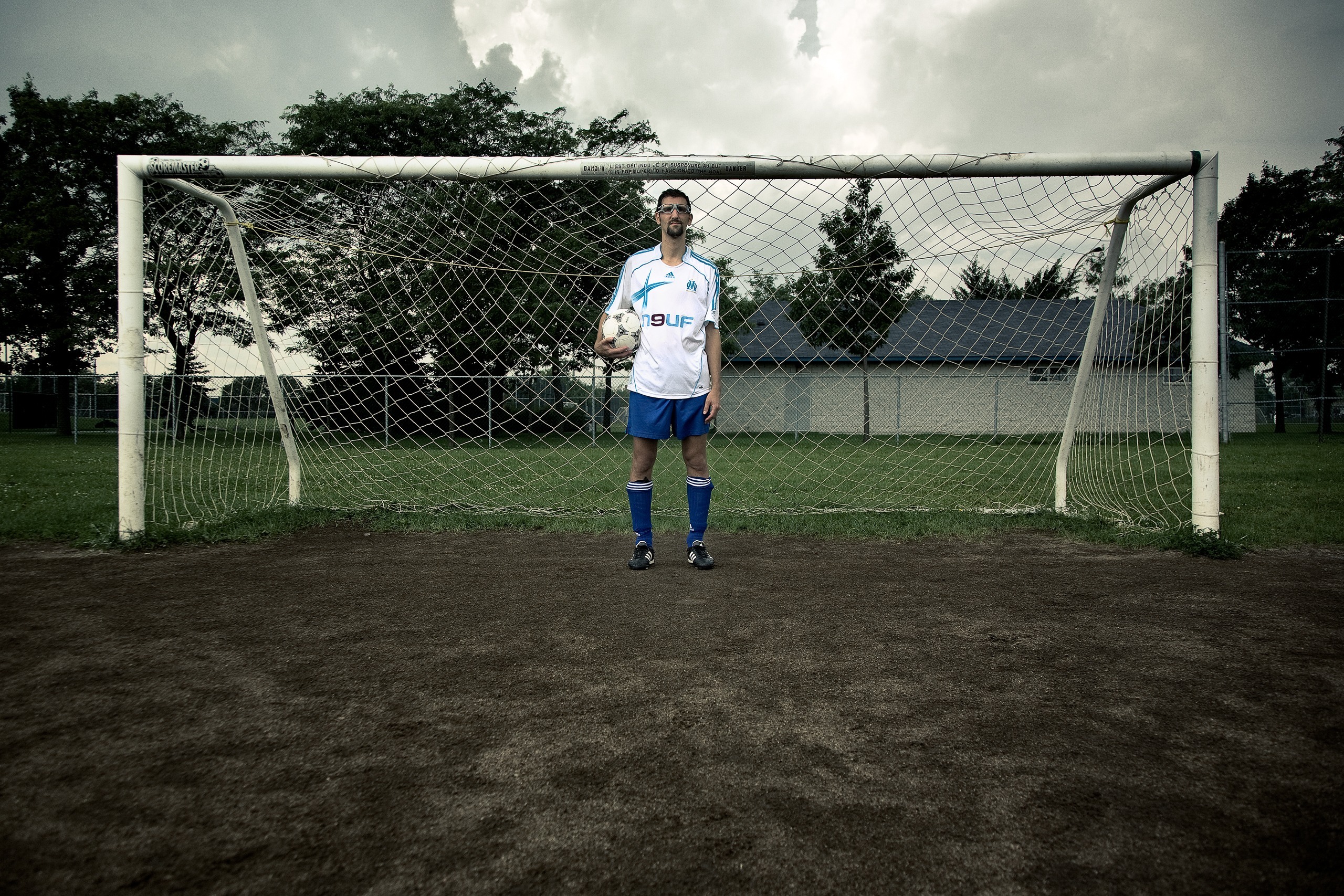 Portrait devant un but de soccer, sur un terrain en terre