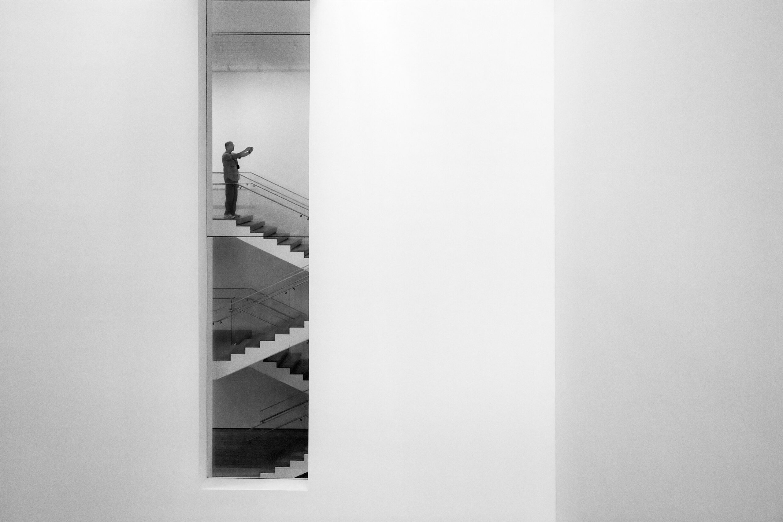 Escalier et visiteur aperçus par une fente dans un mur blanc, MoMA, New York
