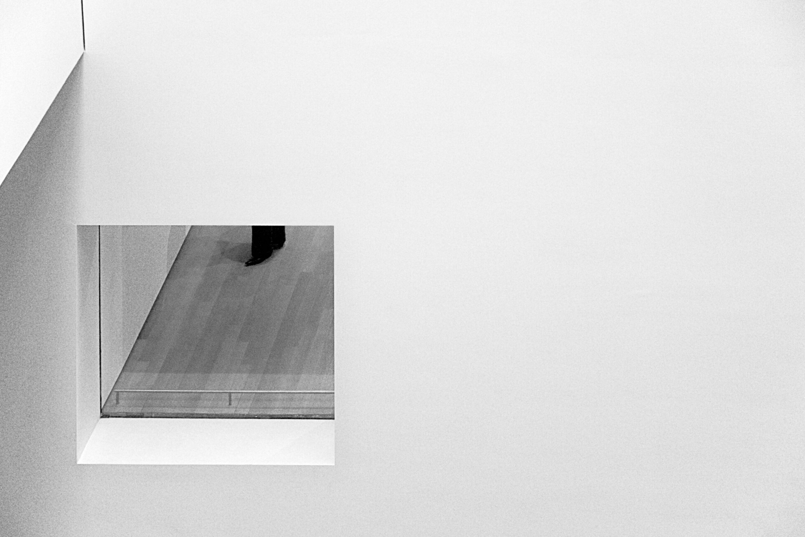 Ouverture dans un mur blanc laissant voir le plancher et un visiteur, MoMA, New York