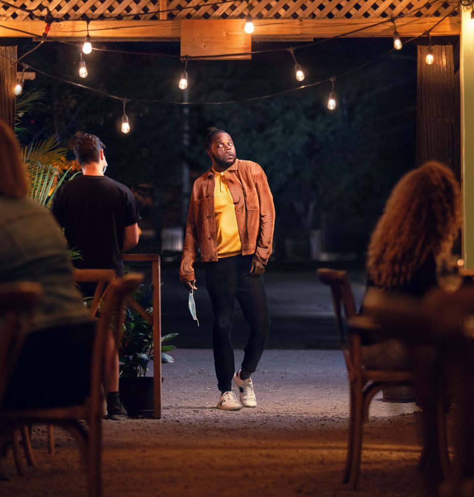 Homme marchant sur une terrasse éclairée de guirlandes, scène du film de la campagne sur le passeport vaccinal, Gouvernement du Québec