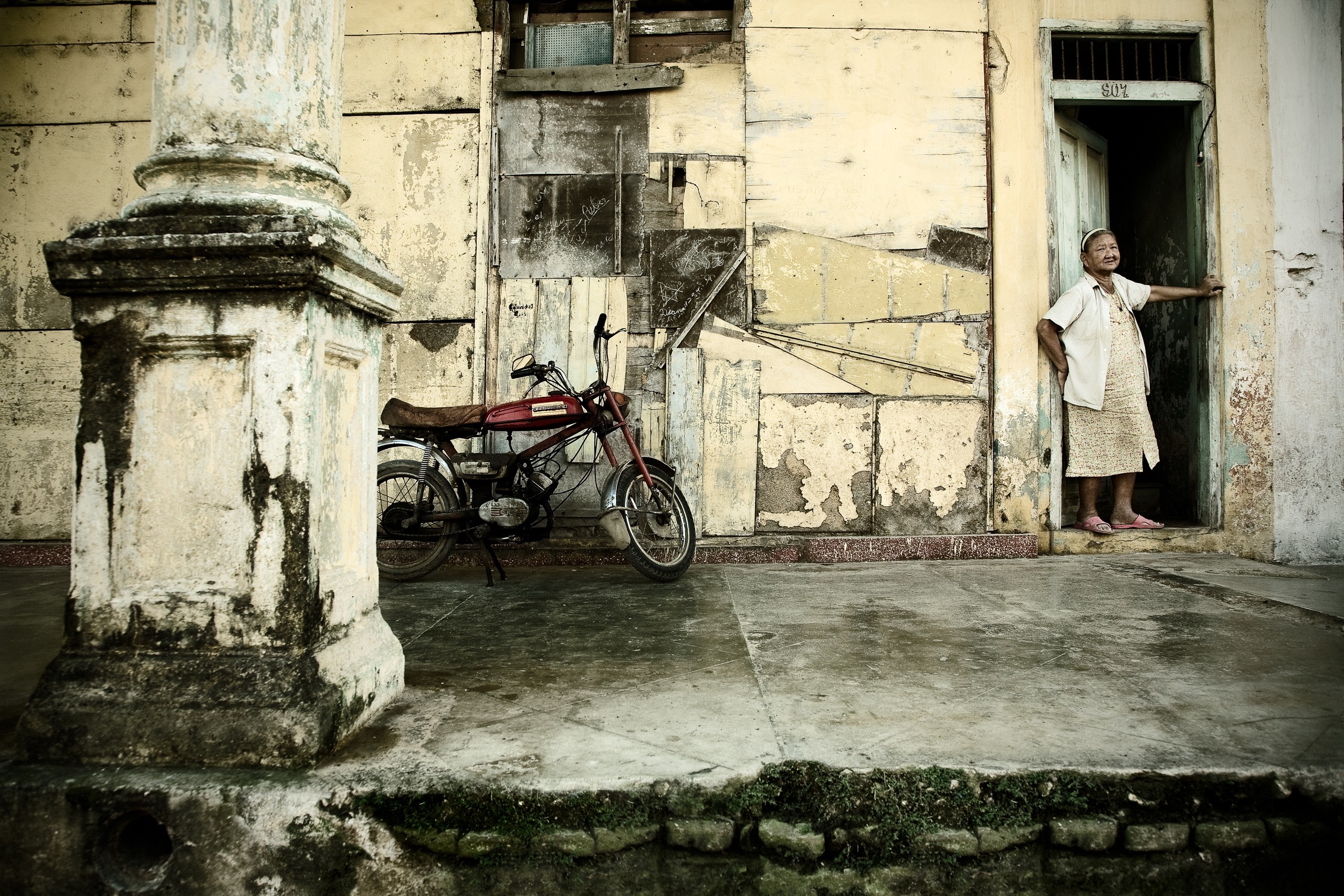 Façade délabrée avec une moto et une femme à sa porte, Remedios, Villa Clara, Cuba