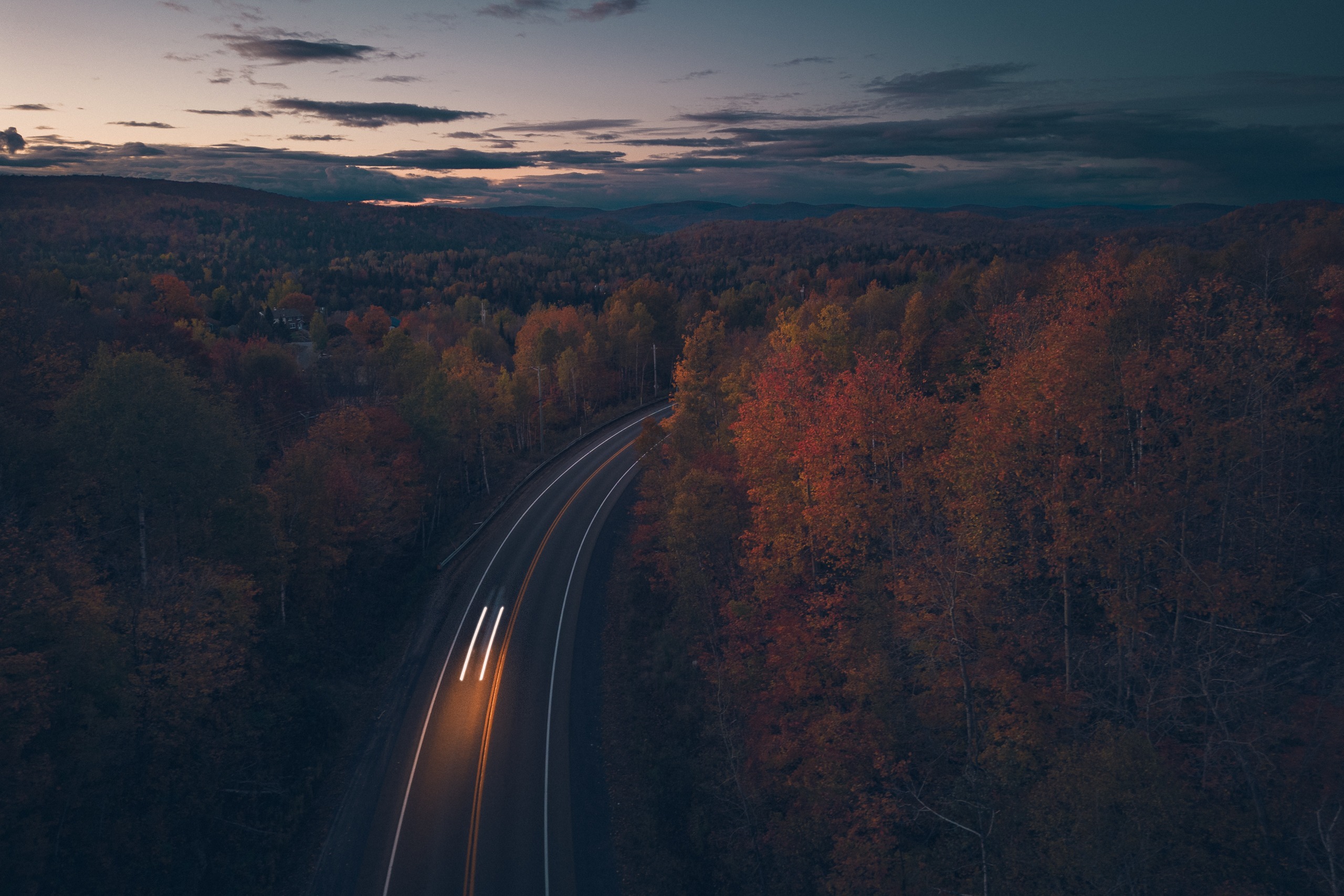 Route traversant une forêt d’automne au crépuscule, traînées de phares, Saint-Adolphe-d’Howard, Laurentides